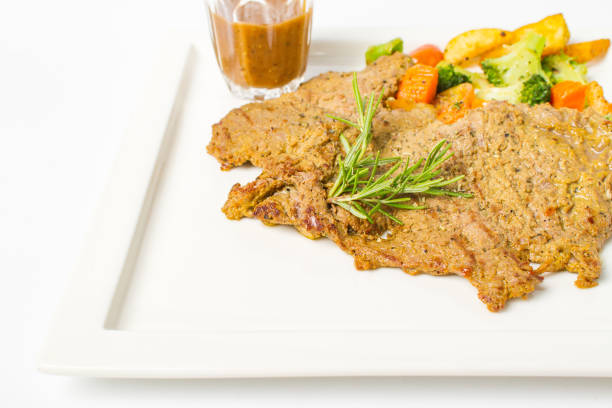 istock Pork steak grilled with black peper sauce and mixed vegetable, rosemary on white background 992576740