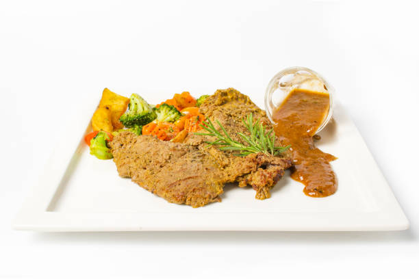 istock Pork steak grilled with black peper sauce and mixed vegetable, rosemary on white background 992576750
