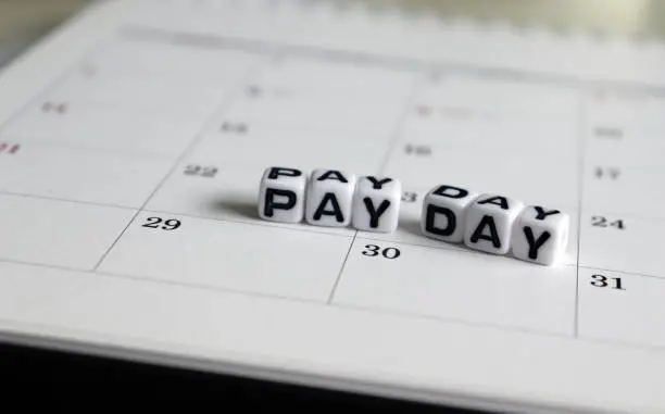 Photo of A white cube arranged in the word ’PAY DAY ' on the calendar.