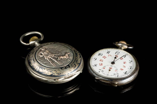 istock Two old pocket watches on a black reflective surface 992608194