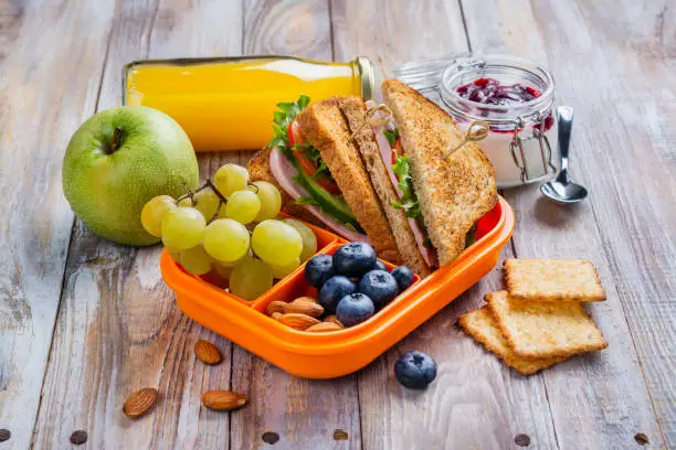 Healthy kids lunchbox with sandwich, fruits and orange juice