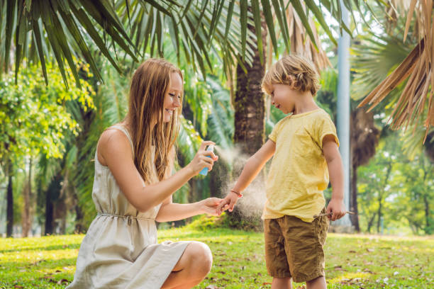 Mom and son use mosquito spray.Spraying insect repellent on skin outdoor stock photo