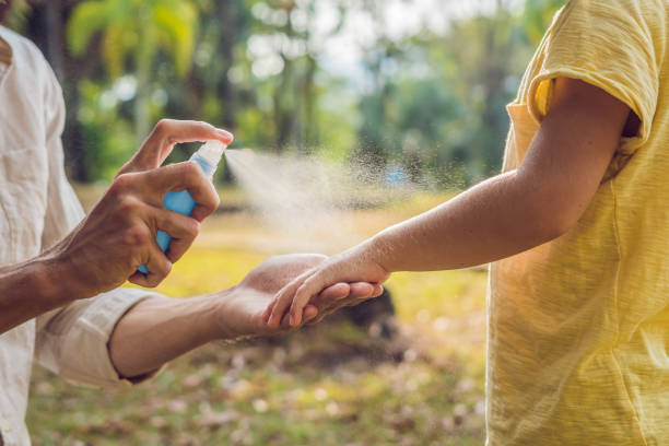 dad and son use mosquito spray.Spraying insect repellent on skin outdoor stock photo