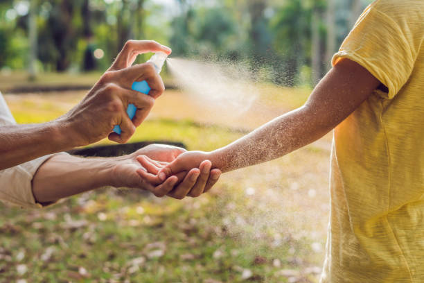 papá e hijo utilizan aerosol del mosquito. rociar repelente de insectos sobre la piel al aire libre - deformado fotografías e imágenes de stock