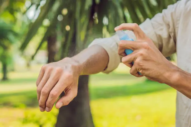 Photo of Young man spraying mosquito insect repellent in the forrest, insect protection