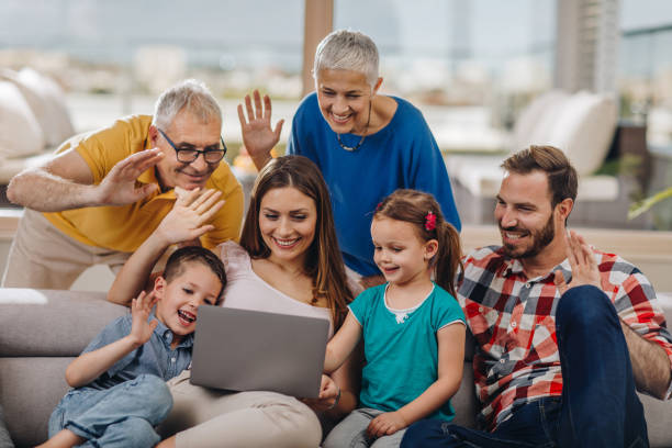 istock Happy multi-generation family waving while using laptop in the living room. 992661782