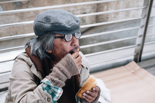 istock Dirty homeless person sit and eating bread 992709720