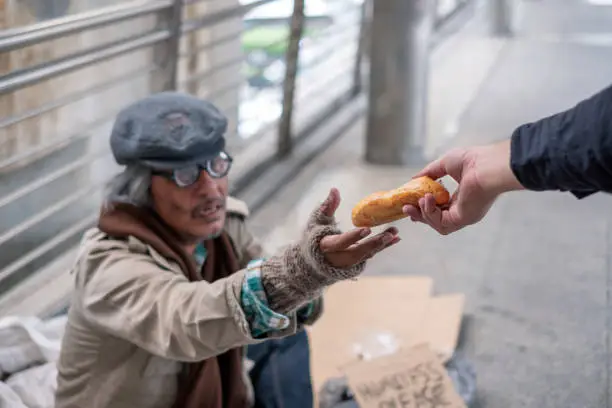 Old man homeless reach out to get bread from donor on corridor bridge