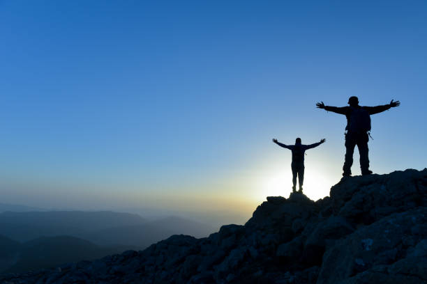 istock Teamwork couple climbing and reaching mountain peak 992710216