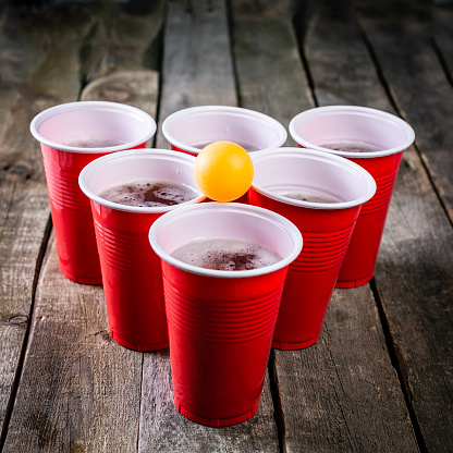 College party sport - beer pong table setting with plastic cups, rustic wood background