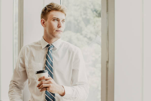 istock Content Business Man on Window Sill With Drink 992714294
