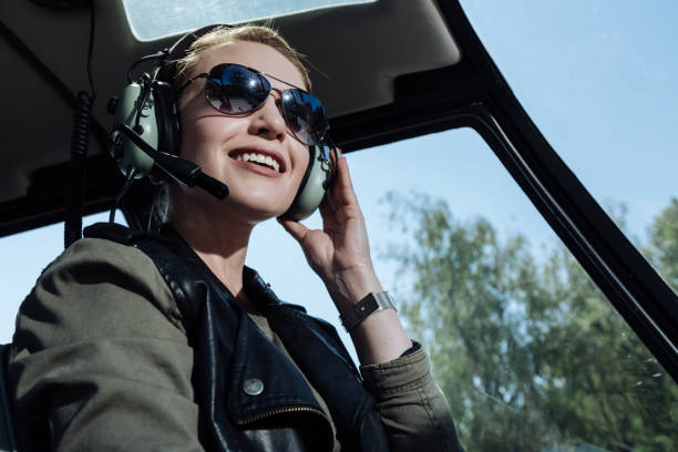 cheerful helicopter pilot smiling while listening to air traffic controller - air vehicle audio imagens e fotografias de stock