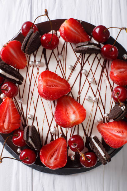 istock Delicious summer cake with strawberries and cherries, decorated with biscuits close-up. vertical top view 992726648