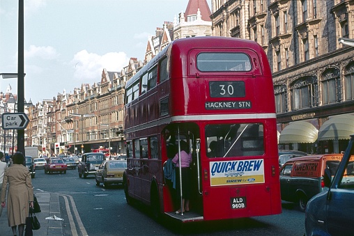 London, England, UK, 1980. The Brompton Road in London. On the right sidewalk is the famous department store Herrods. Furthermore: pedestrians, double-decker bus, cars, traffic and buildings.