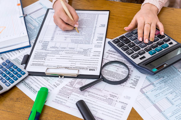 istock 1040 form with female hands and calculator 992734714