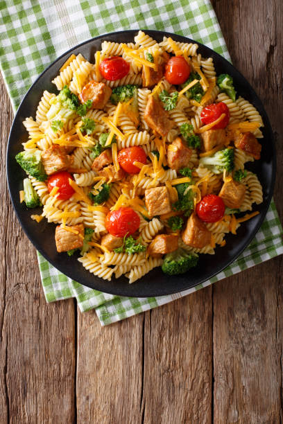 istock Fusilli pasta with pork, broccoli, tomatoes and cheese cheddar close-up on the table. Vertical top view 992734784