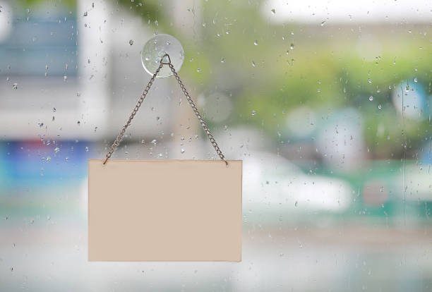istock Rain drop with empty sign board hanging on glass door with copy space. 992744240