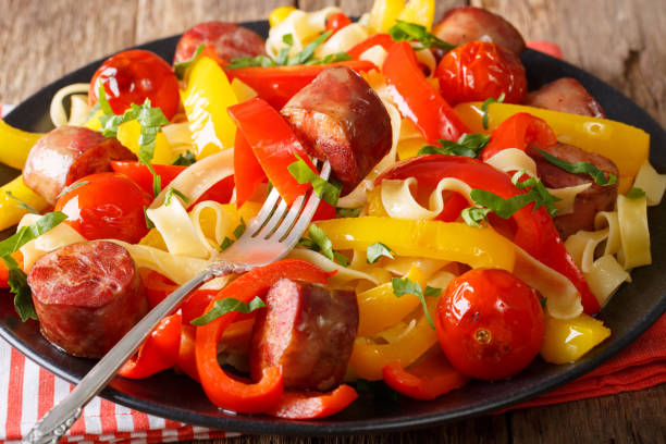 istock Fettuccine pasta with pepper, fried sausages and tomatoes close-up. horizontal 992757856
