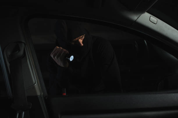 istock male robber in black balaclava with flashlight looking into car 992759310