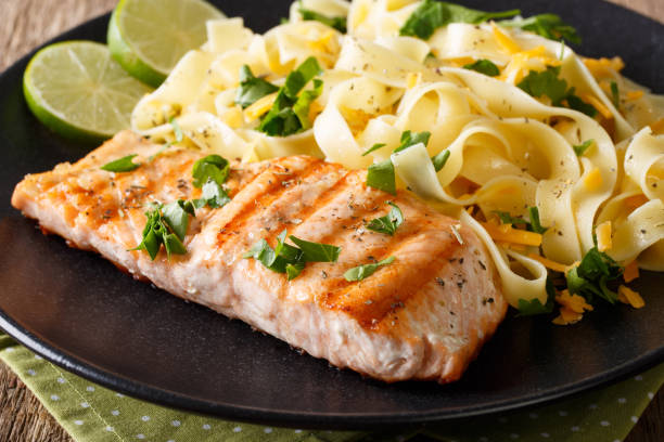istock grilled salmon garnished with fettuccini pasta with cheese, herbs closeup. horizontal 992759340