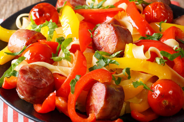 istock Delicious food: stewed pepper with fried sausages, noodles and tomatoes close-up. horizontal 992761672