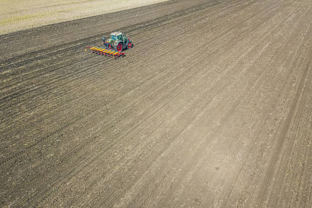 istock Farmer seeding crops at field. Seeding Aerial View. 992783284