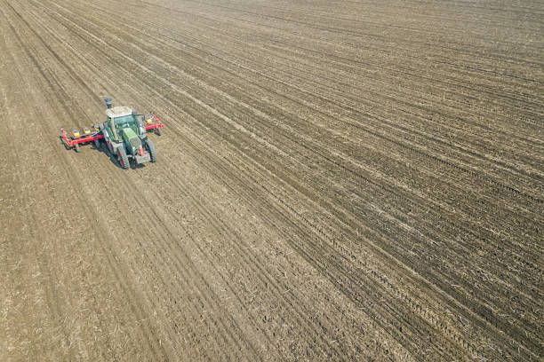 istock Farmer seeding crops at field. Seeding Aerial View. 992786370