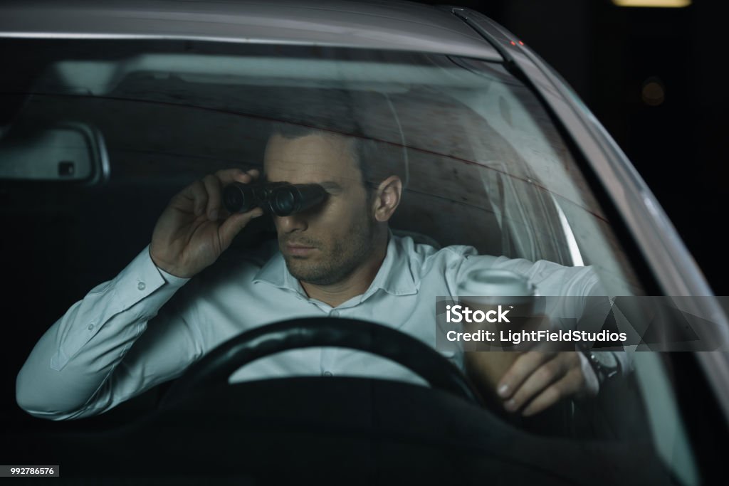 Undercover Male Agent Doing Surveillance By Binoculars And Drinking Coffee  In Car Stock Photo - Download Image Now - iStock