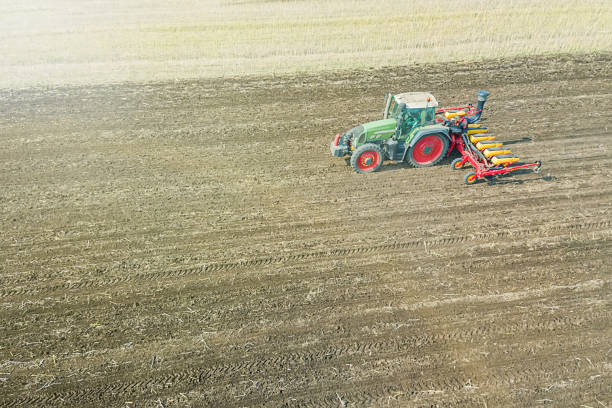 istock Farmer seeding crops at field. Seeding Aerial View. 992786578