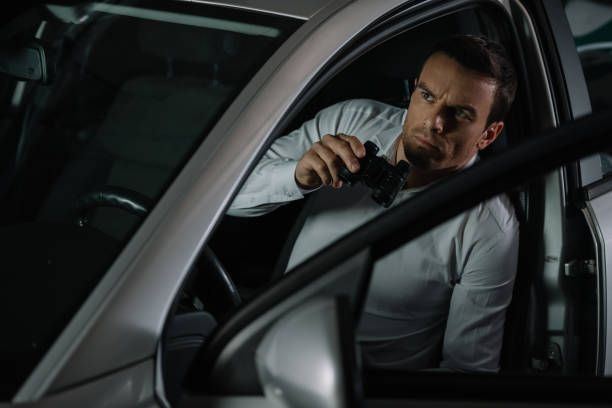 istock focused undercover male agent doing surveillance by binoculars from his car 992786920
