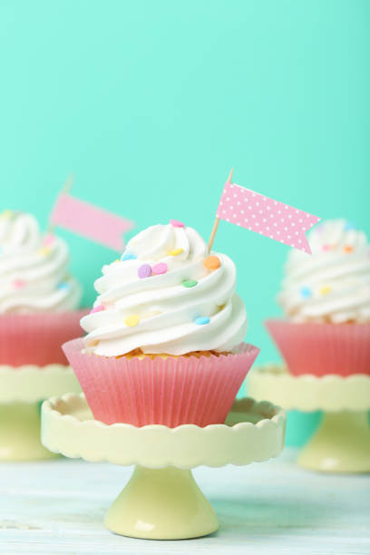 istock Tasty cupcakes on cake stand on green background 992790366