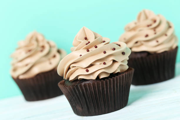 istock Tasty cupcakes on a white wooden table 992790550