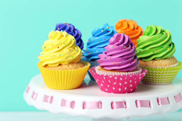 istock Tasty cupcakes on cake stand on green background 992790942