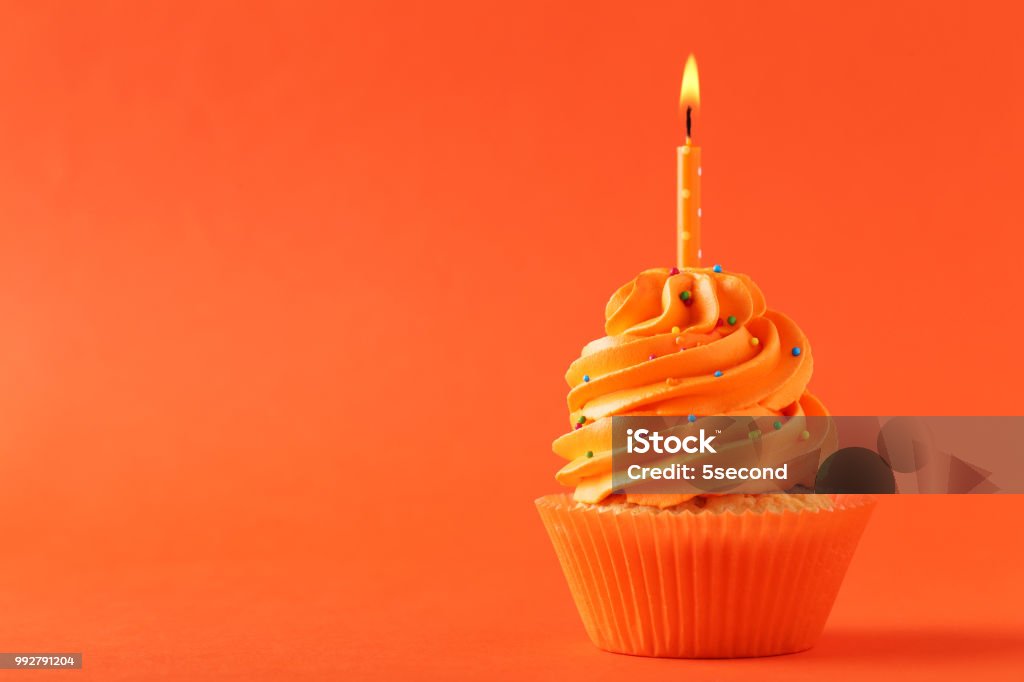 Leckere Cupcake mit Kerze auf orangem Hintergrund - Lizenzfrei Orange - Farbe Stock-Foto