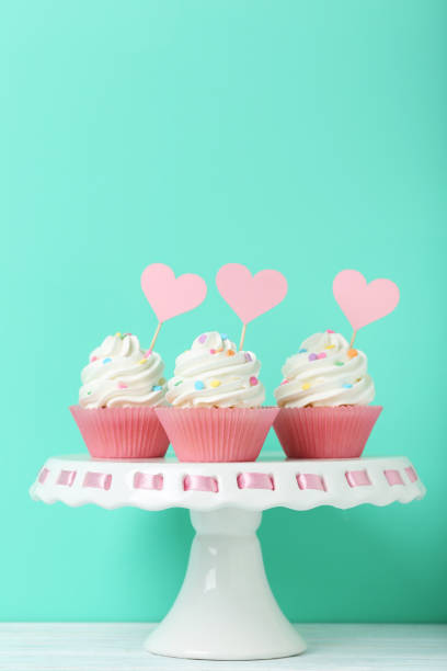 istock Tasty cupcakes on cake stand on green background 992791410