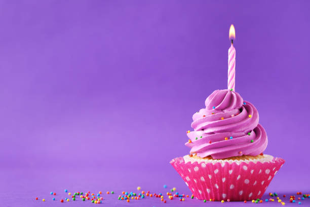 istock Tasty cupcake with candle on a purple background 992793932