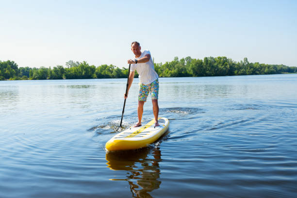 istock Joyful man sails on a SUP board in large river 992794298
