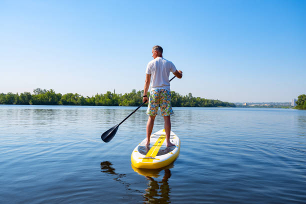 istock Adult man sails on a SUP board in large river 992794344