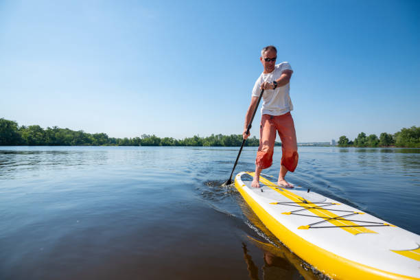 istock Joyful man in sunglasses sails on a SUP board in large river 992794346