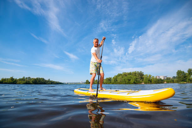 istock Joyful man sails on a SUP board in large river 992795432