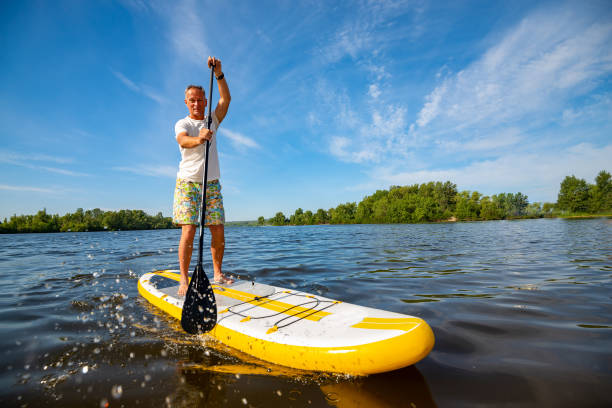 neşeli adam sup kurulu eğitim - paddle surfing stok fotoğraflar ve resimler