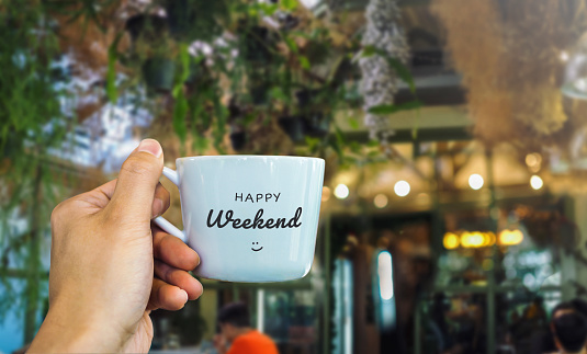 Happy weekend text on mug with cafe view