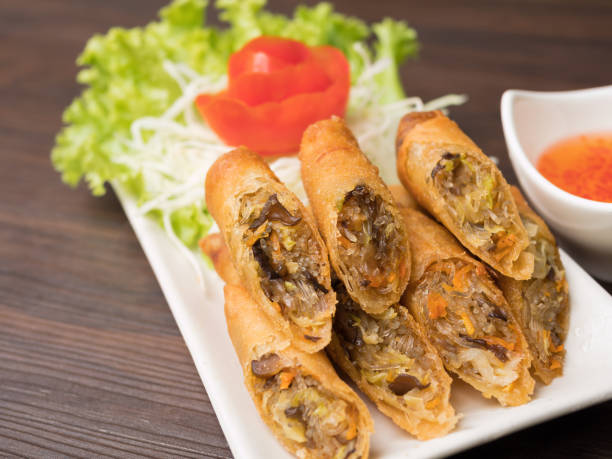 istock Close up of a fried spring roll on white plate with sweet sauce and fresh vegetable 992808126