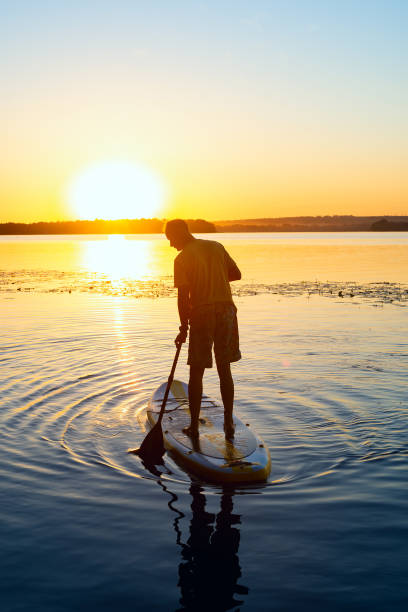 istock Silhouette of a man who sails on a SUP board 992815616