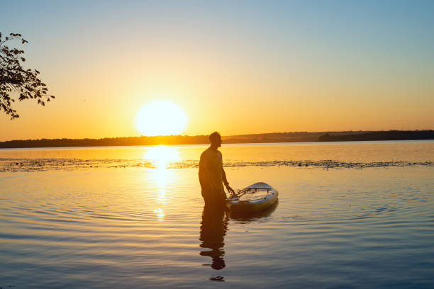 istock Man relaxes next to a SUP board in a large river 992815622