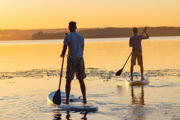 istock Men, friends sail on a SUP boards in a large river 992815646