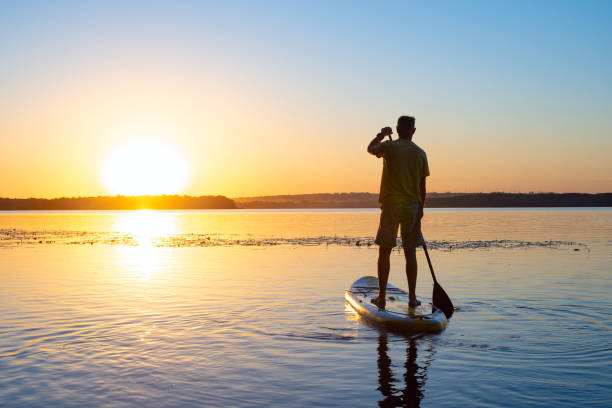istock Man sails on a SUP board in a large river during sunrise 992815694