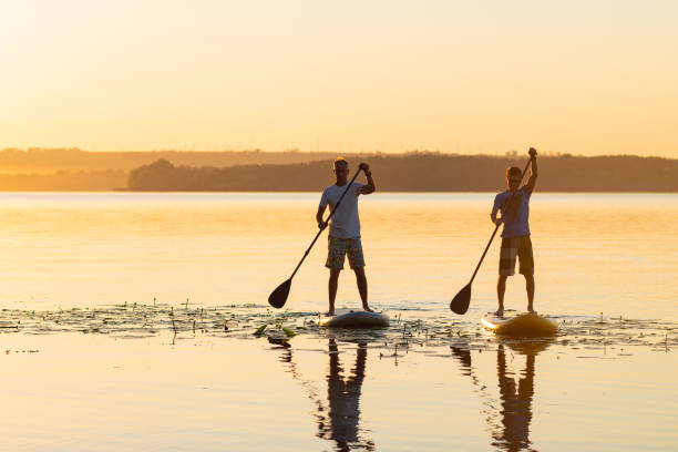 istock Men, friends sail on a SUP boards in a large river 992815772