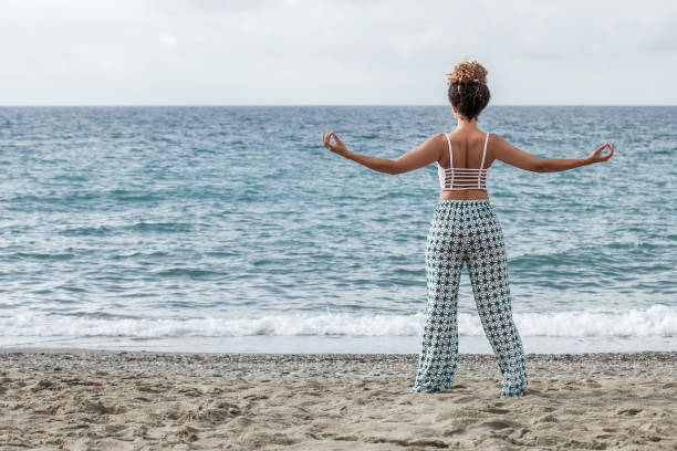 istock Woman portrait practicing yoga on the beach while looking at sea 992815844