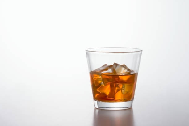 istock Glass of brandy and ice cubes on white background 992823638